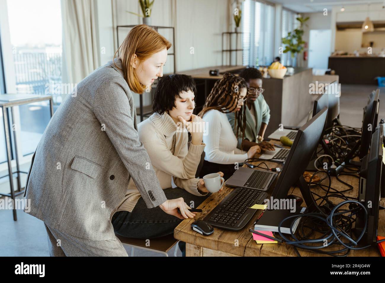 Manager discussing with female programmer over computer at desk in startup office Stock Photo