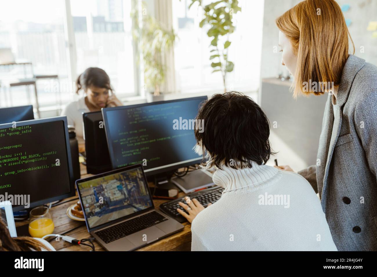 Manager discussing with programmer over computer at desk in office Stock Photo