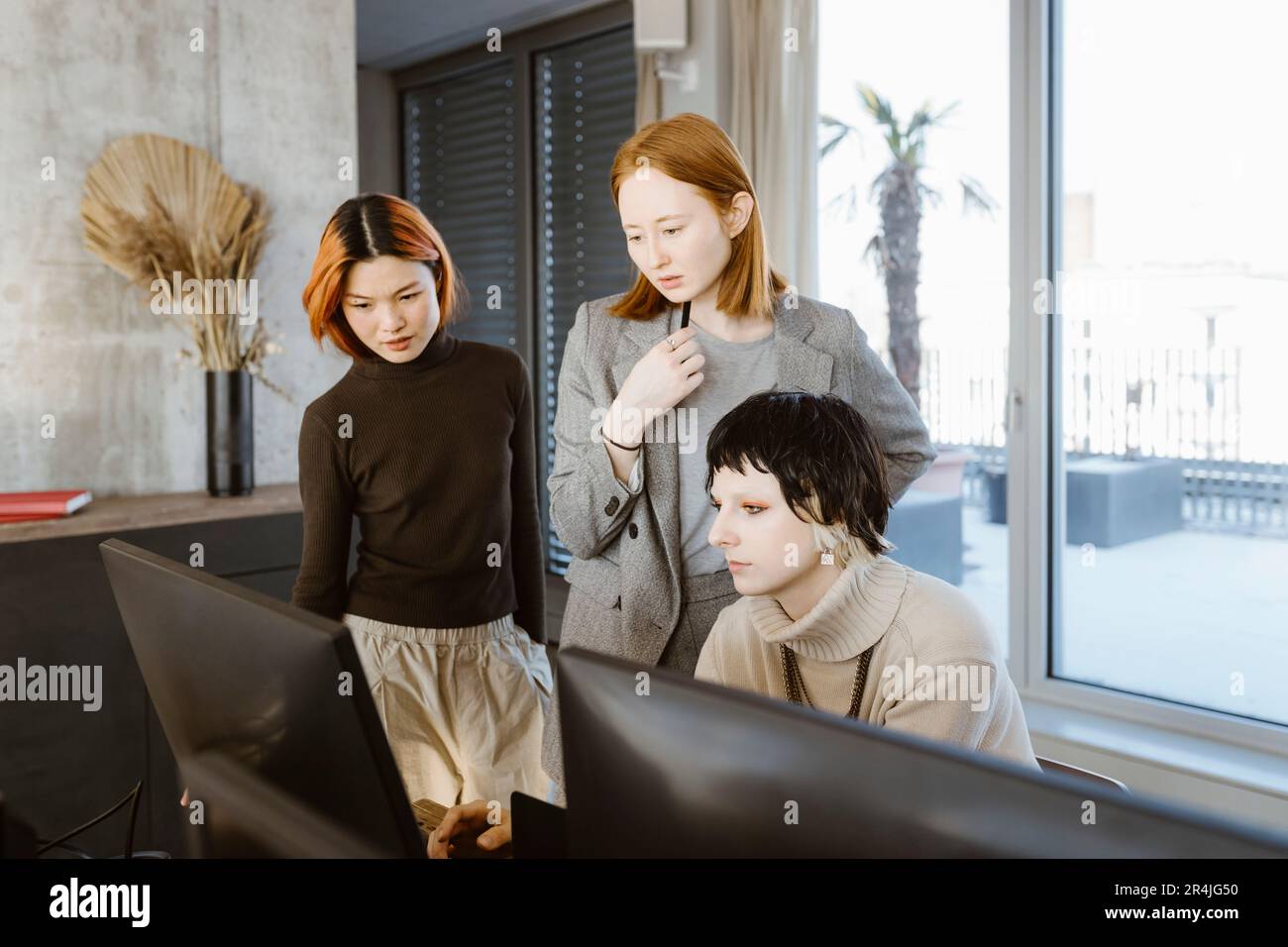 Multiracial female programmers discussing over computer at desk in startup office Stock Photo