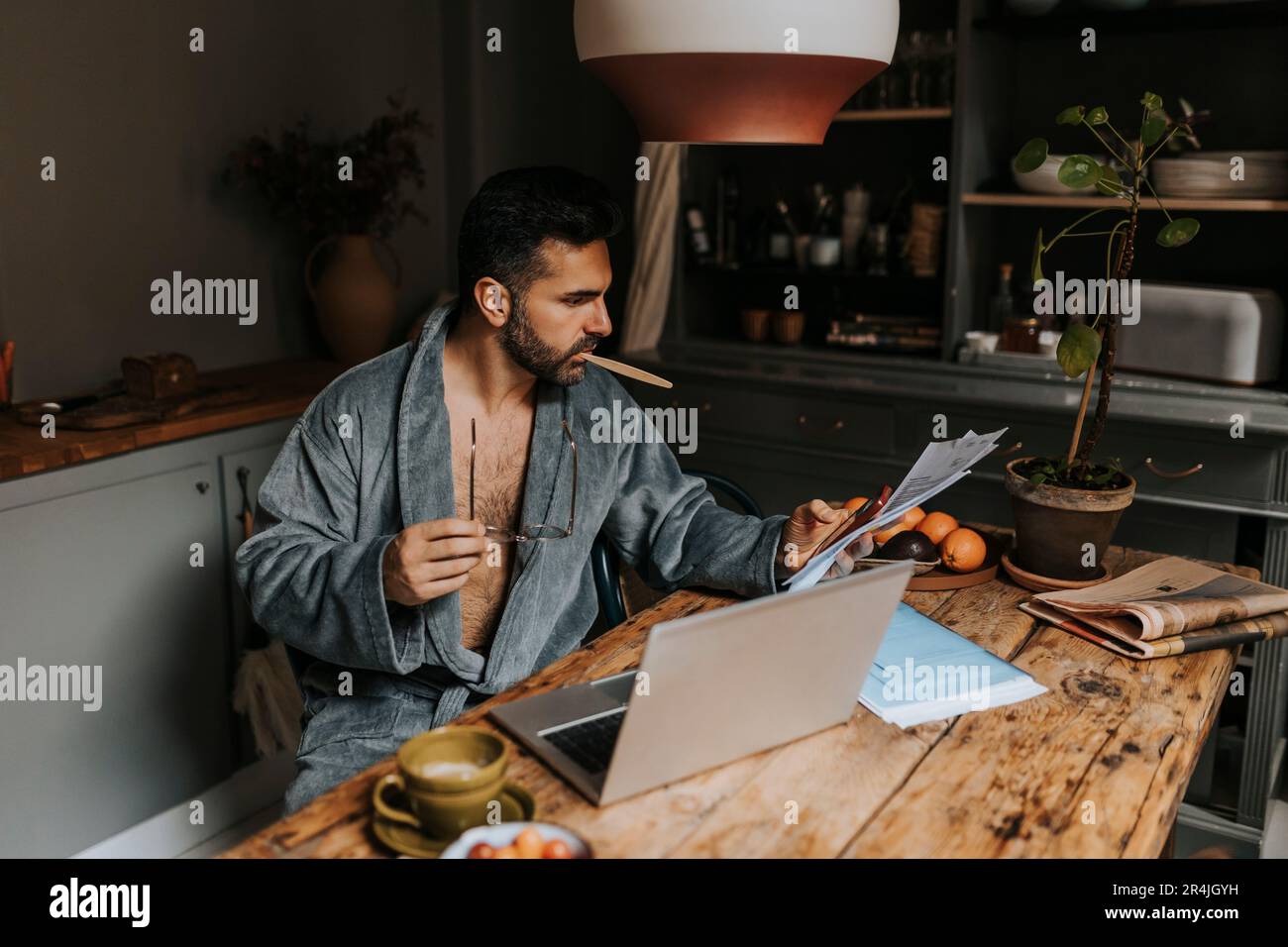 Man using smart phone while holding financial bills at dining table Stock Photo