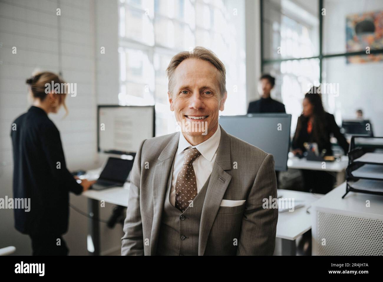 Portrait of smiling mature businessman wearing suit at office Stock ...