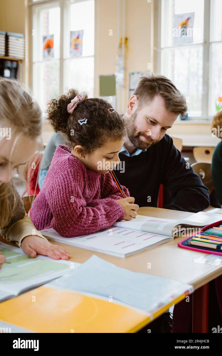 Schoolgirl solving maths equation by male teacher in classroom Stock ...