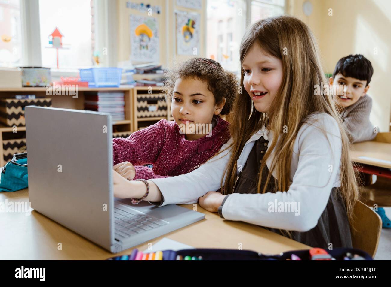 Schoolgirls using laptop together at desk in classroom Stock Photo - Alamy