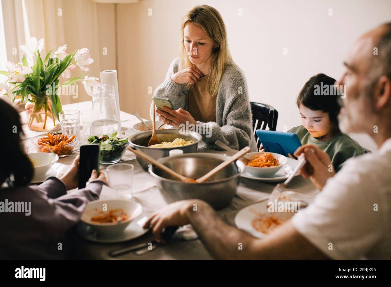 Family using gadgets while sitting at dining table Stock Photo