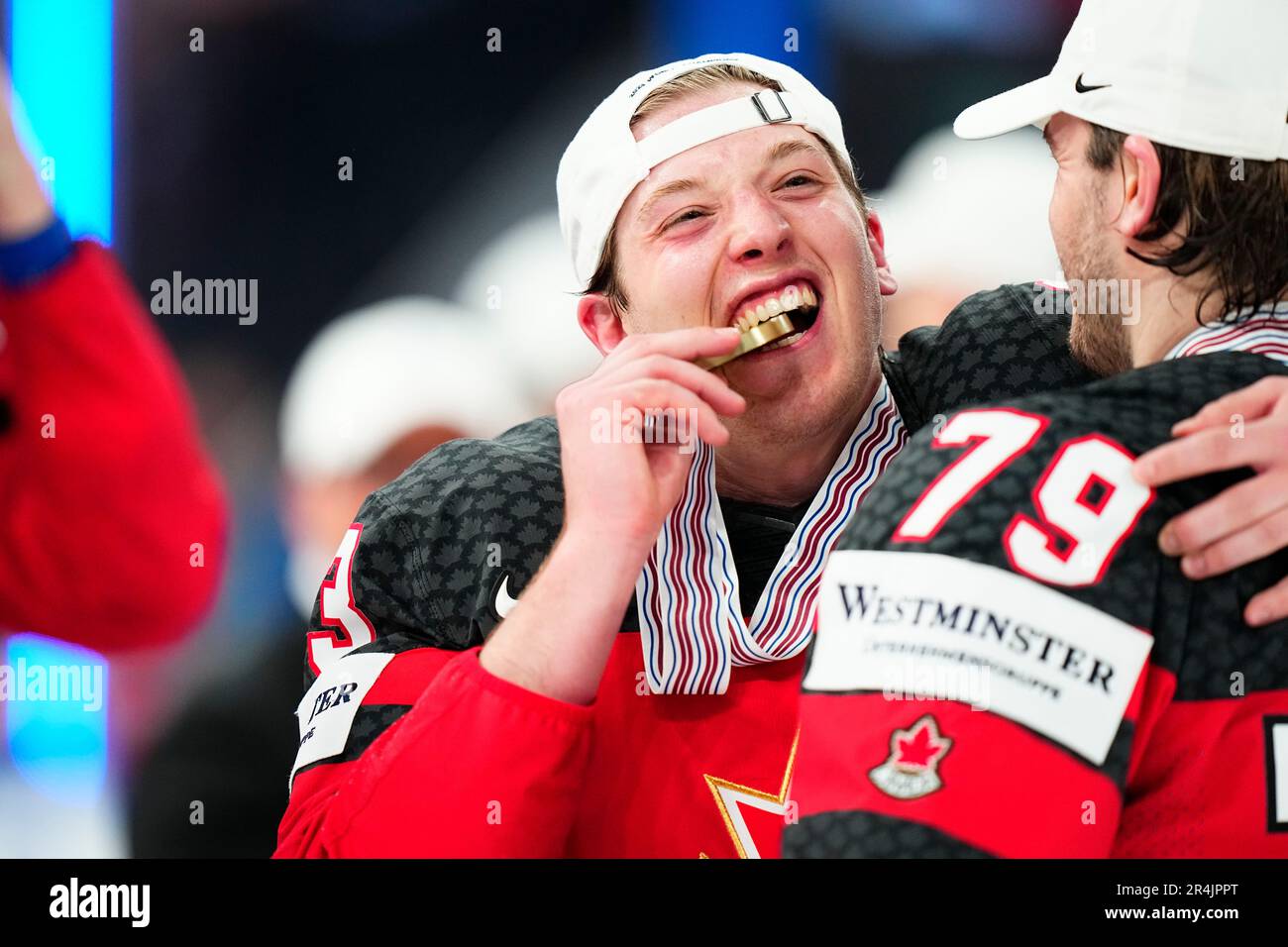 Canada's Jake Neighbours (63) bites his gold medal during a ceremony after defeating Germany for