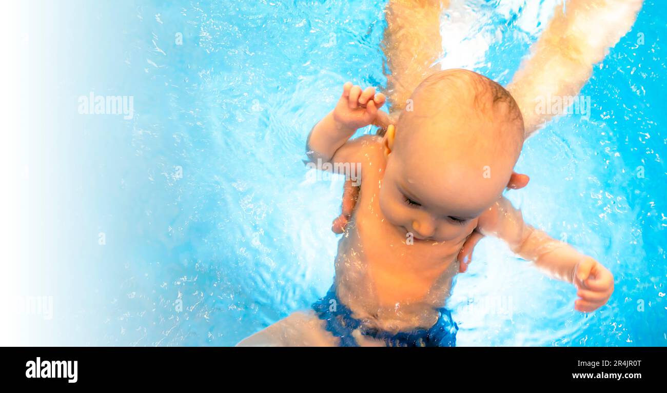 Adorable baby girl enjoying swimming in a pool with her mother early development class for