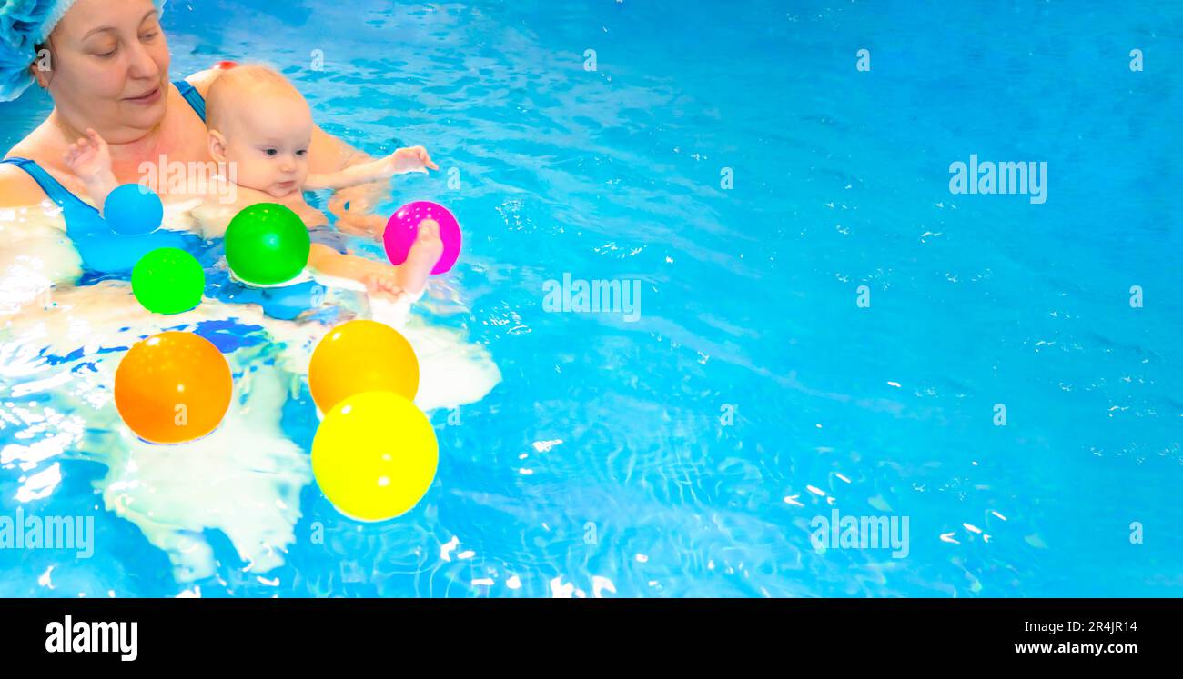 Adorable baby girl enjoying swimming in a pool with her mother early development class for