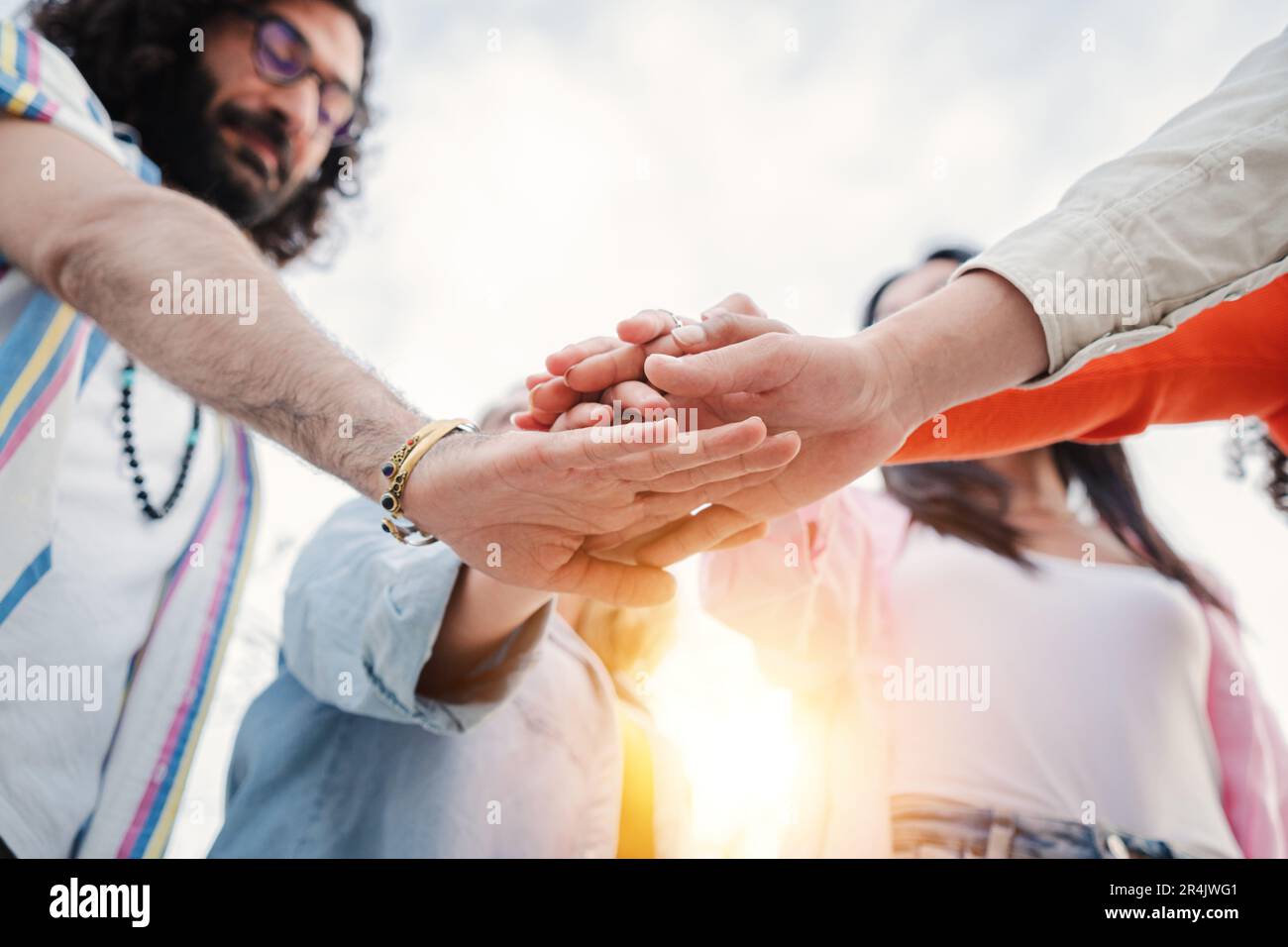 Low angle view of group of young people stacking hands together ...