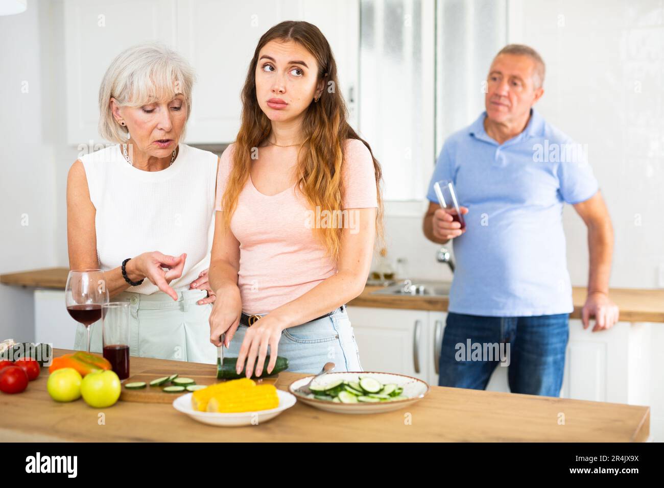 Mother-in-law teaches young daughter-in-law to cook dinner in kitchen