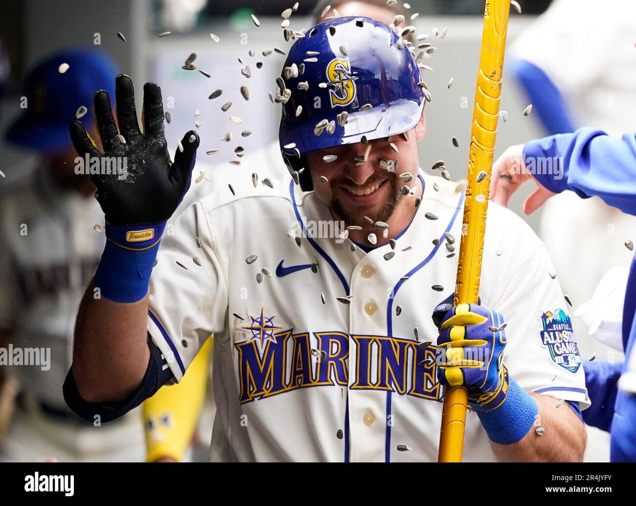 Seattle Mariners designated hitter Cal Raleigh holds a trident in the  dugout after hitting a home run against the Pittsburgh Pirates as teammates  throw sunflower seeds at him during the fourth inning