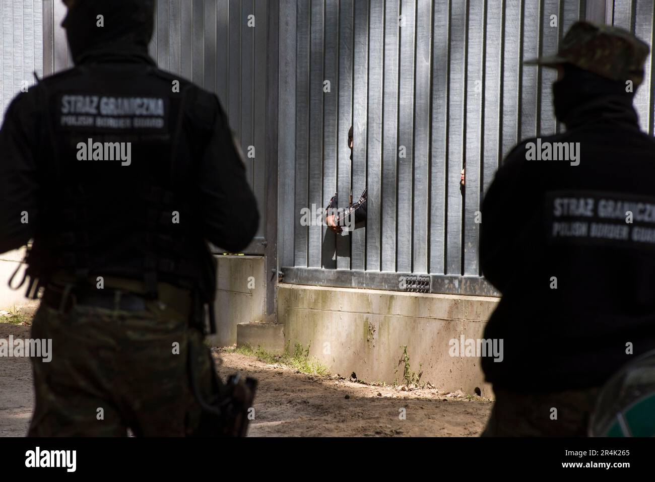 Polish border guards are seen watching the migrants who are stuck at the Polish border wall in Bialowieza. A group of 30 migrants and refugees from Iraq and Syria seeking asylum, including more than 10 children, has been stuck at Poland's border wall with Belarus for three days. Belarusian border guards are not allowing them to turn back to Belarus. Activist Marta Staniszewska form the Grupa Granica (Border Group) organization, who spoke with the migrants, said, that 'Belarusian services told the migrants if they return, they will be beaten, or that they will even kill them”. Stock Photo