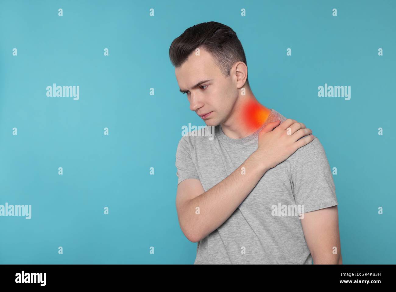 Arthritis symptoms. Young man suffering from pain in his neck on light