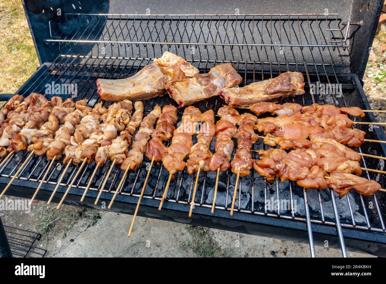 Pork barbecue cooking in a grill. Pork is pushed onto wooden skewers to