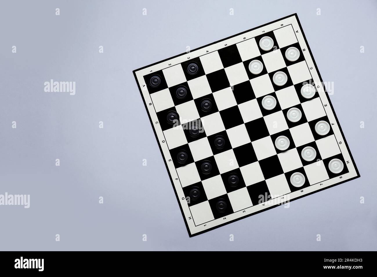 Black and white checkerboard with game pieces on light grey background ...