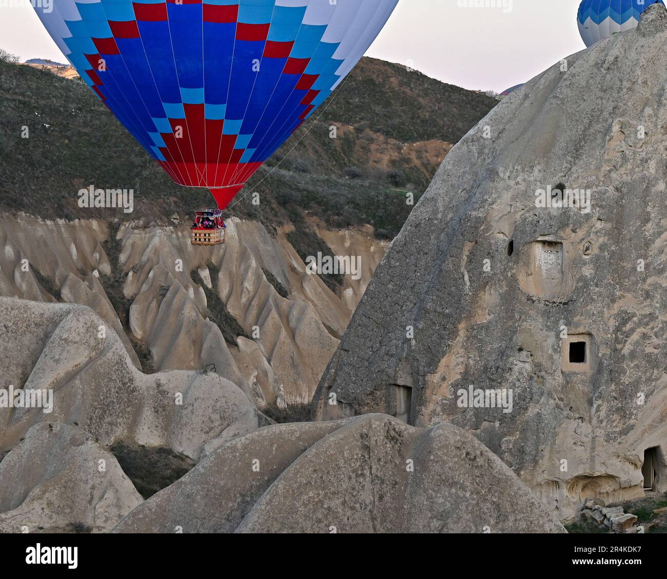 Hot air balloons flying past the ancient cave houses of the Zelve Open Air Museum, Capadoccia, Turkey Stock Photo