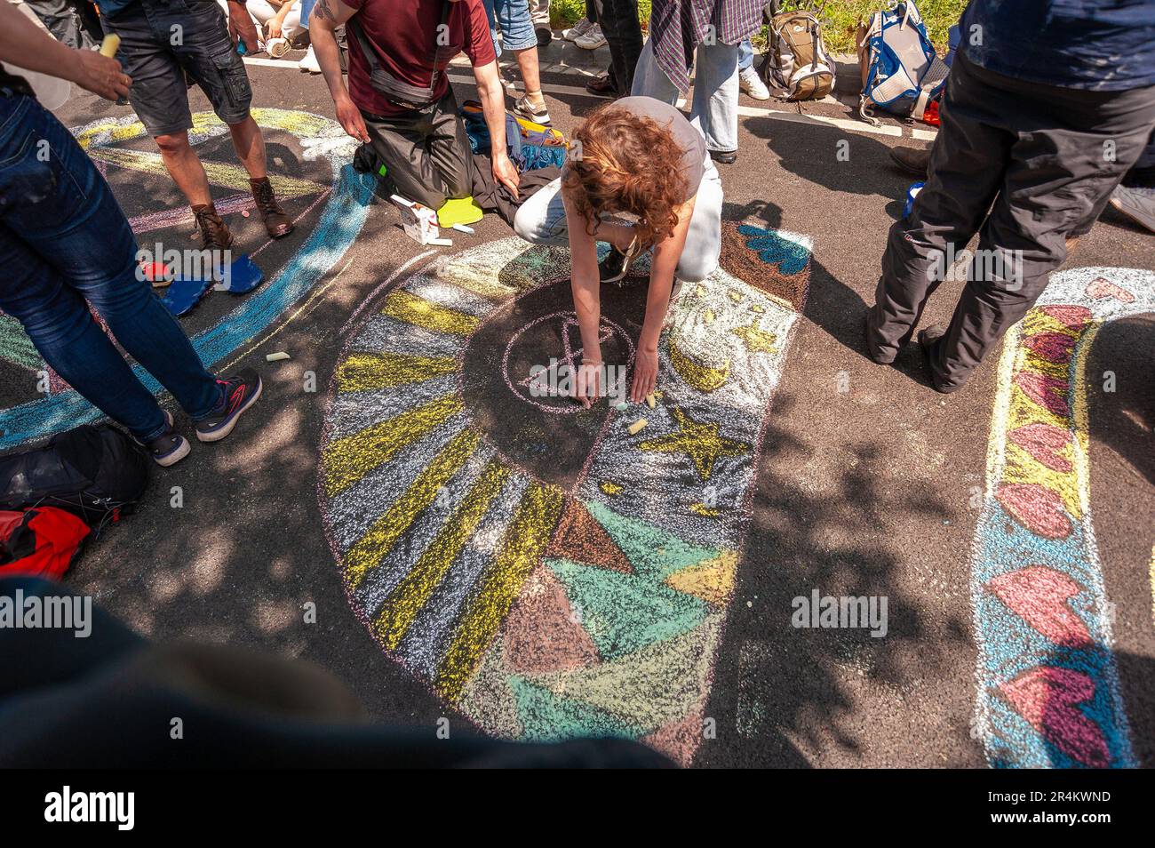 A young girl draws colourful graffiti and Extinction Rebellion logo on tarmac, during the demonstration. Police used water cannon against Extinction Rebellion demonstrators and their supporters, in The Hague. This was the seventh time this section of the A12 on the Utrechtsebaan has seen similar protests and was banned by the municipally. Police used water cannon on low pressure in an attempt to disperse the demonstrations within minutes of them gathering. The protesters came ready with, umbrellas, protective clothing and, taking advantage of the warm spell; a few girls wore bikinis, and on mo Stock Photo