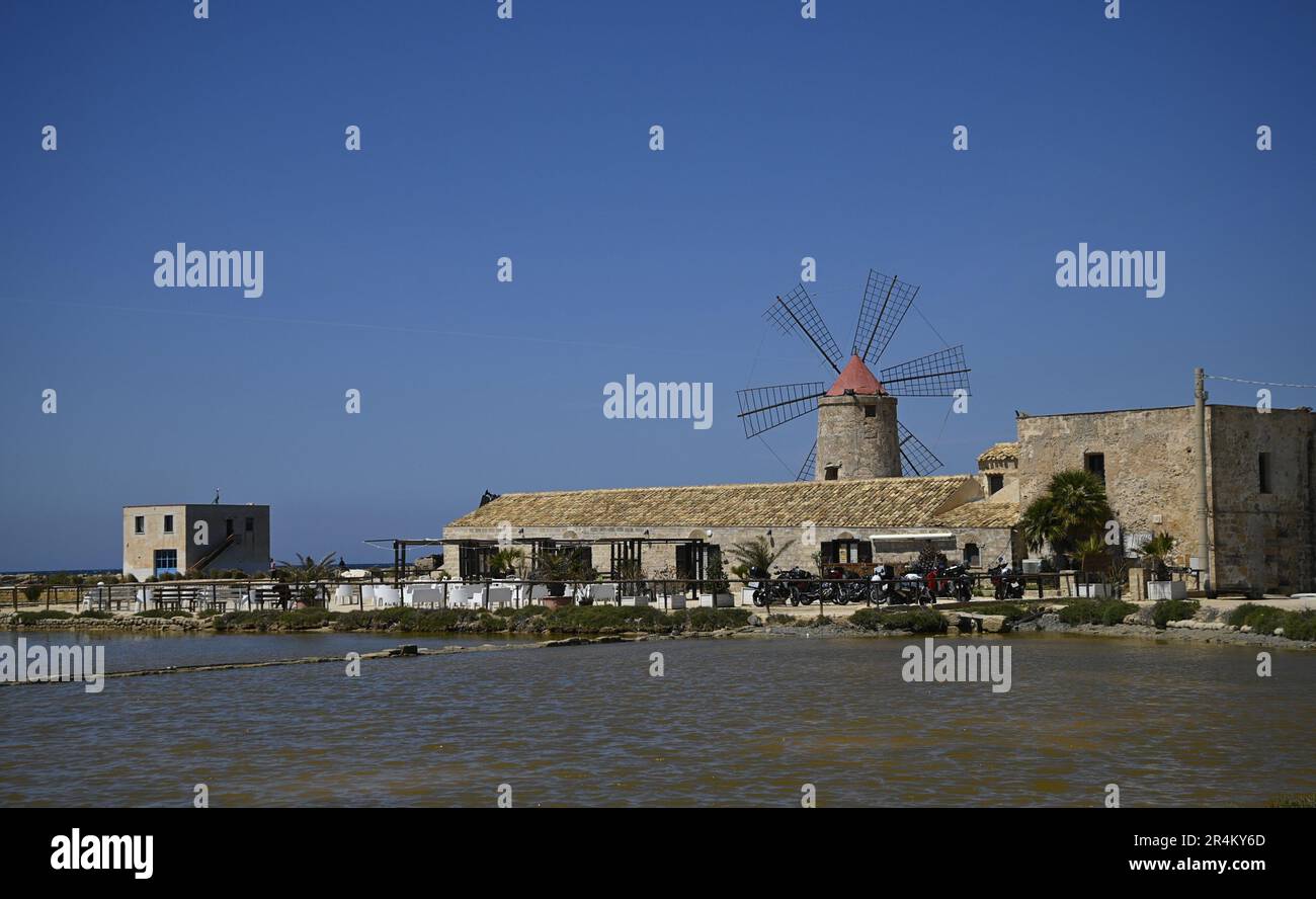 Landscape with scenic view of a traditional mill in the salt pan Salina Calcara, Nubia Natural Reserve of Trapani and Paceco, Sicily. Stock Photo