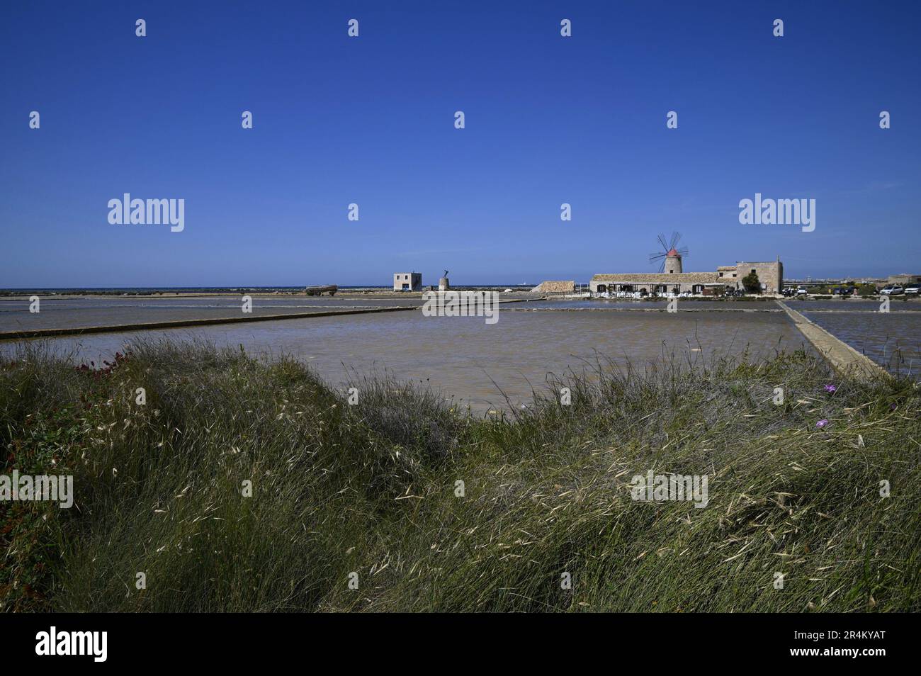 Landscape with scenic view of a traditional mill in the salt pan Salina Calcara, Nubia Natural Reserve of Trapani and Paceco, Sicily. Stock Photo
