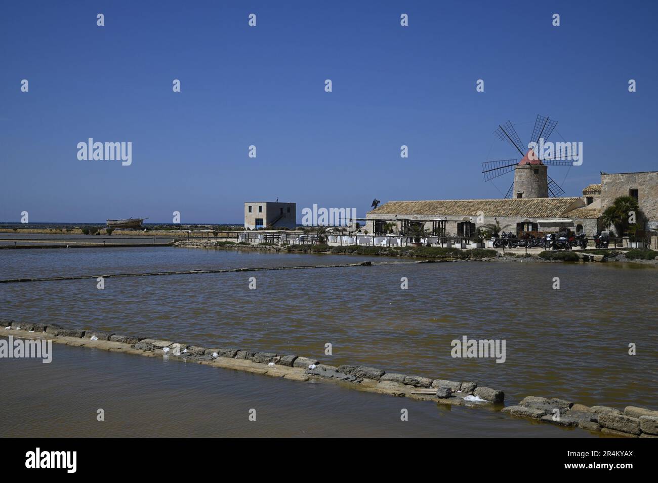 Landscape with scenic view of a traditional mill in the salt pan Salina Calcara, Nubia Natural Reserve of Trapani and Paceco, Sicily. Stock Photo