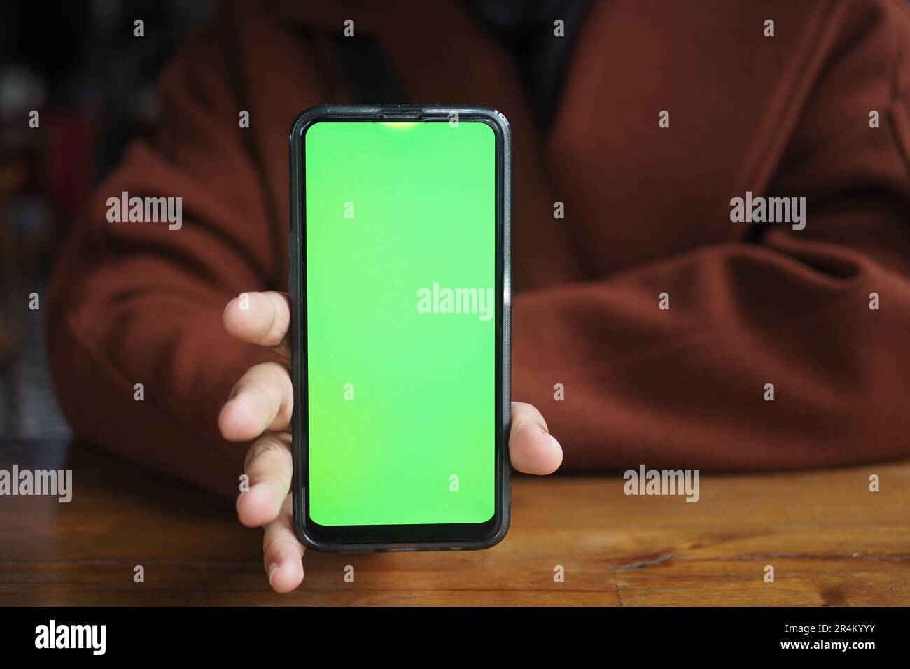 Holding Blank Cell Phone In Hand Showing Green Screen To Camera Stock
