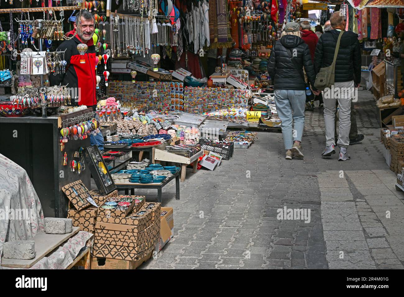 A tour group walks past souvenir shops and food stalls along the approach to the Goreme Open-Air Museum, Turkey. Stock Photo