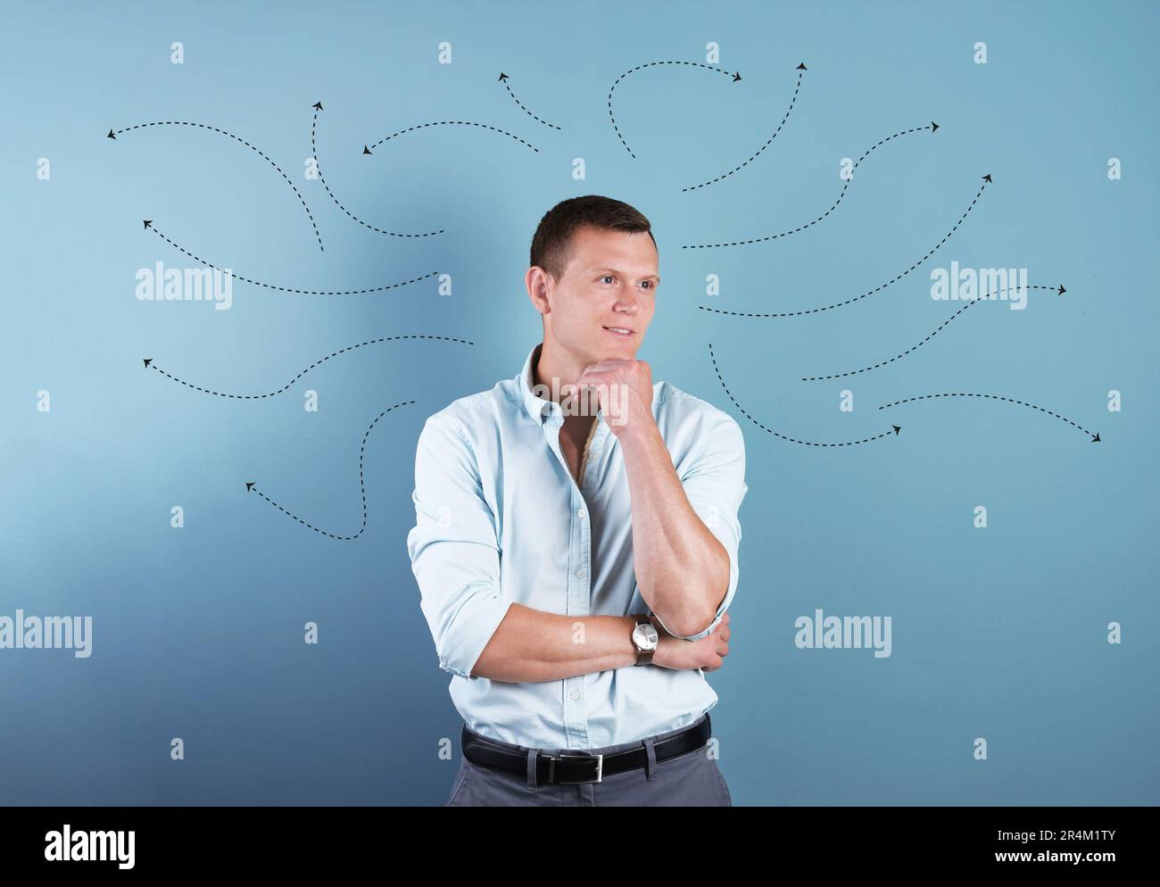 Choice in profession or other areas of life, concept. Making decision, thoughtful young man surrounded by drawn arrows on color background Stock Photo