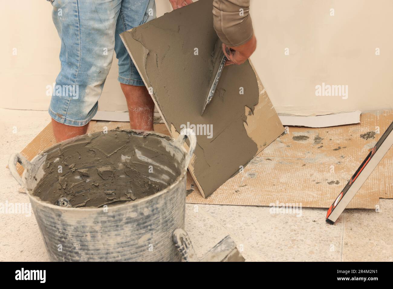 Worker spreading adhesive mix over tile with spatula, closeup Stock Photo