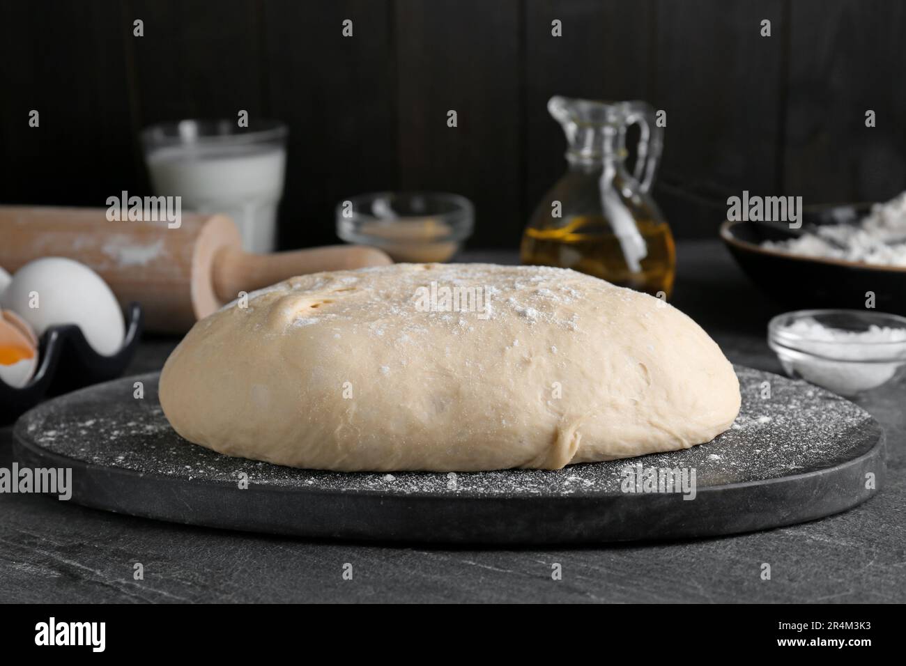 Fresh yeast dough with flour on black table Stock Photo - Alamy