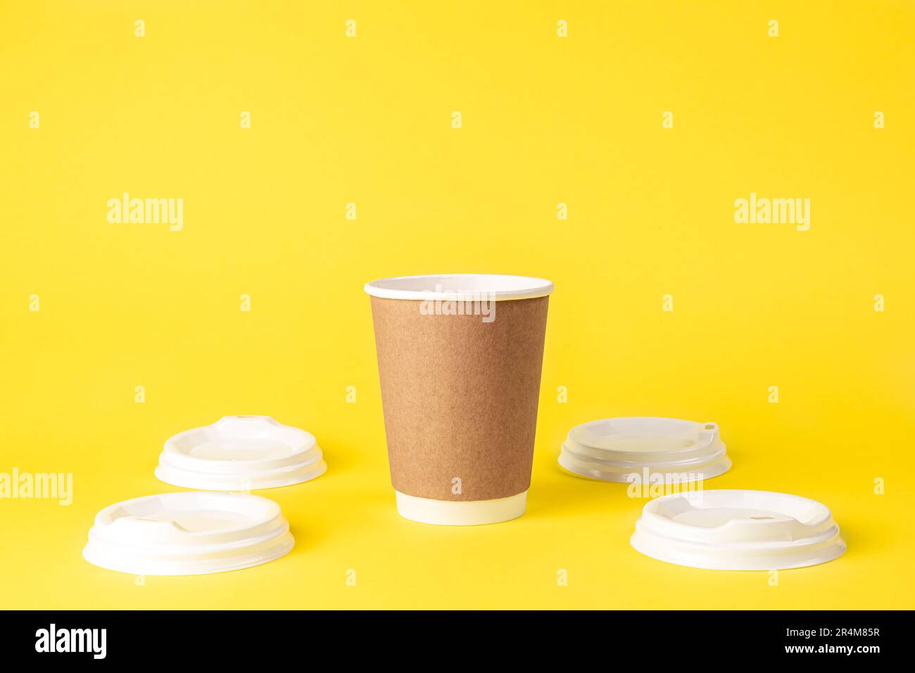 Paper cup and plastic lids on a yellow background isolated Stock Photo
