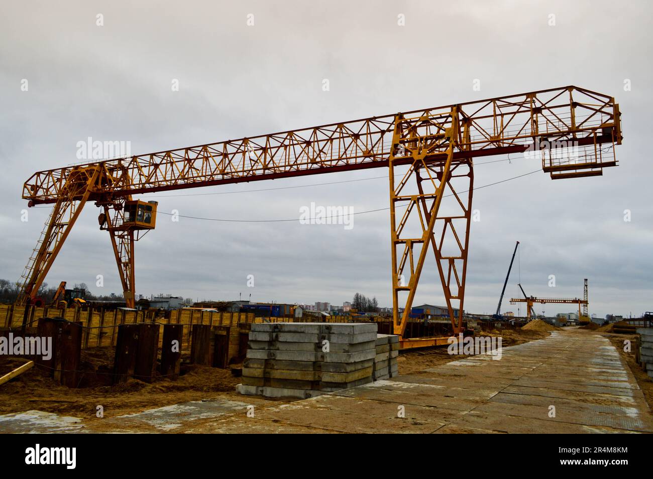 High heavy yellow metal iron load-bearing construction stationary industrial powerful gantry crane of bridge type on supports for lifting cargo on a m Stock Photo