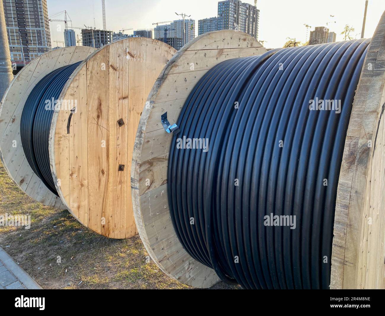 Large round wooden spools of bobbins with wires, black electric cables