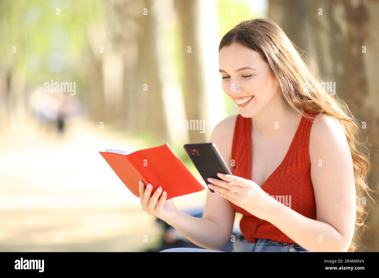 Happy woman checking paper agenda and phone in a park Stock Photo