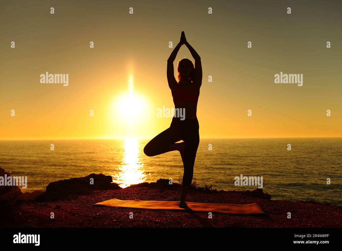 Silhouette of a yogi doing yoga exercise at sunset on the beach Stock Photo