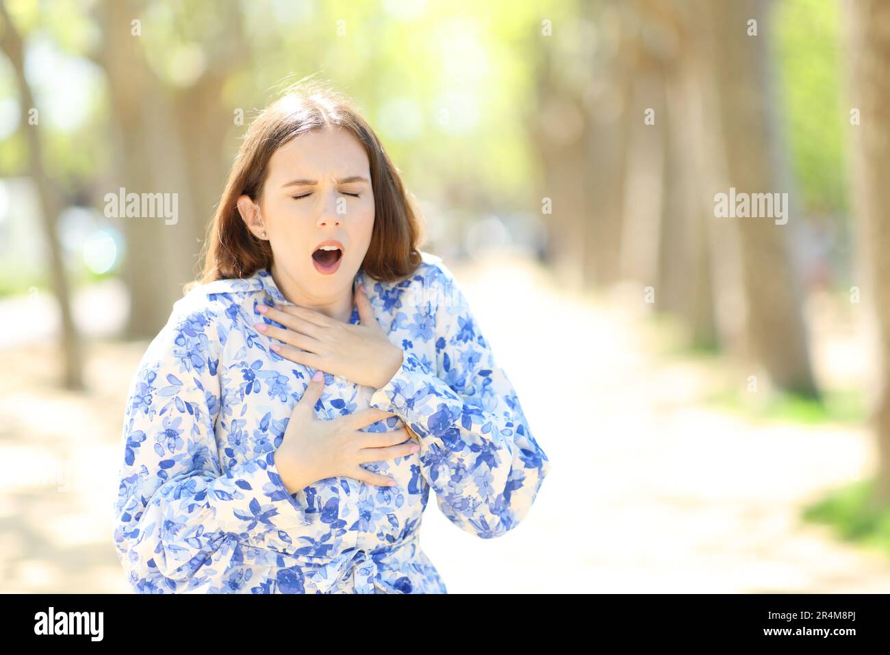 Front view portrait of a stressed woman choking in a park Stock Photo