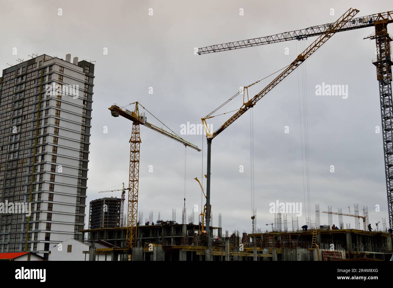 Construction of large modern monolithic frame houses, buildings using industrial construction equipment and large high cranes. Construction of the bui Stock Photo