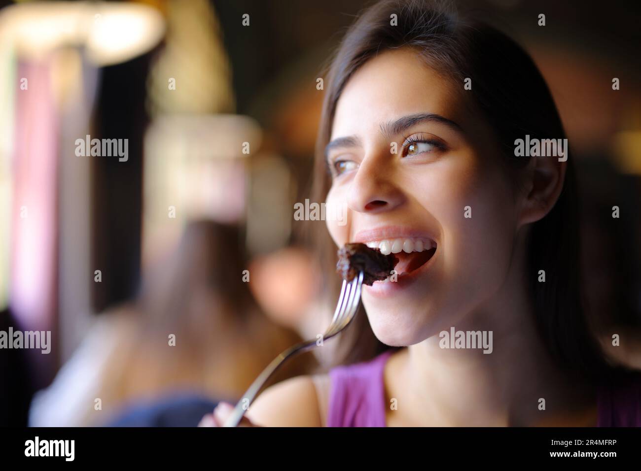 Happy woman eating meat using fork in a restaurant Stock Photo Alamy