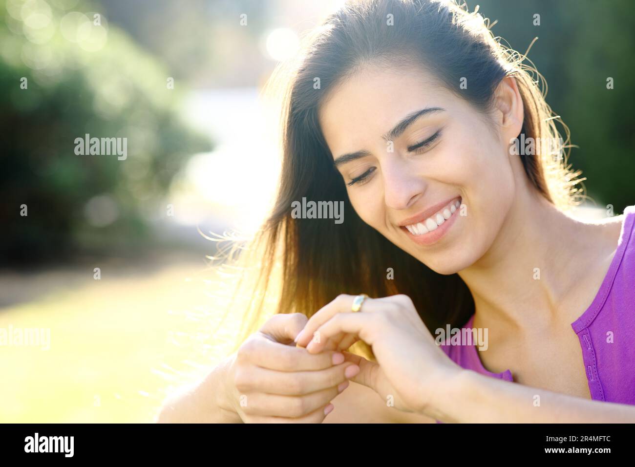 Happy fiancee looking at engagement ring in a park Stock Photo