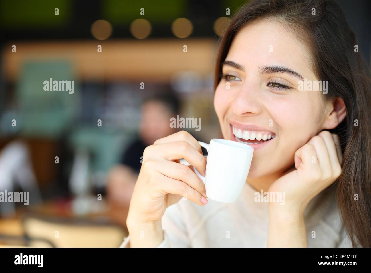 Happy woman drinking coffee and laughing in a restaurant interior Stock Photo