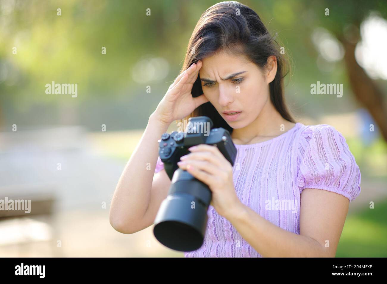 Worried photographer checking result on camera in a park Stock Photo ...