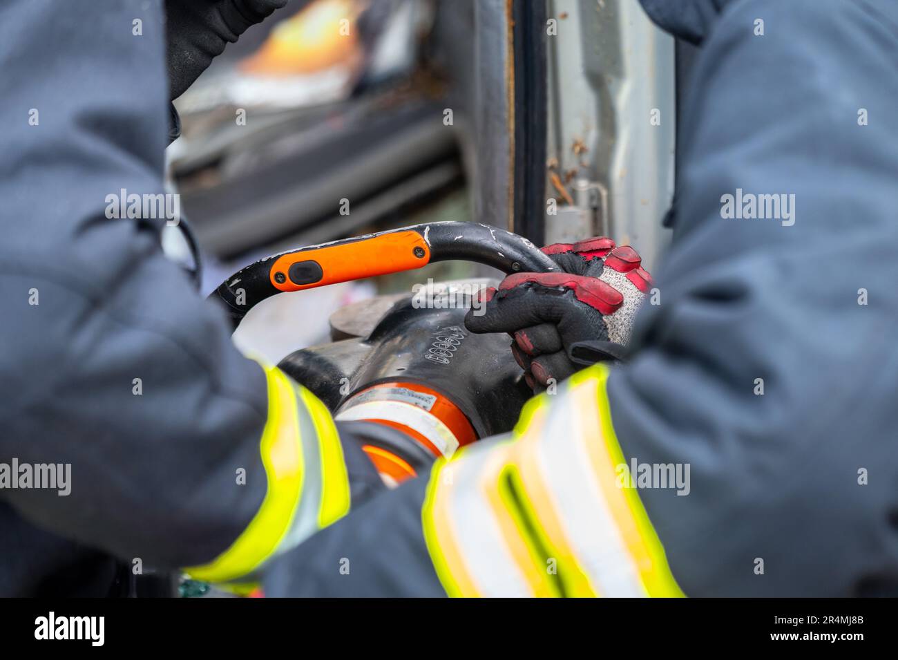 Firefighters using hydraulic tools during a rescue operation training. Rescuers unlock the passenger in car after accident. High quality photography. Stock Photo