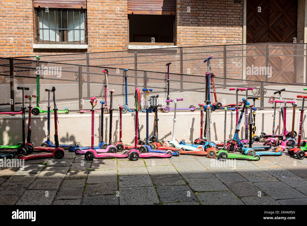 Children's scooters parked outside a Junior school in Venice Stock Photo