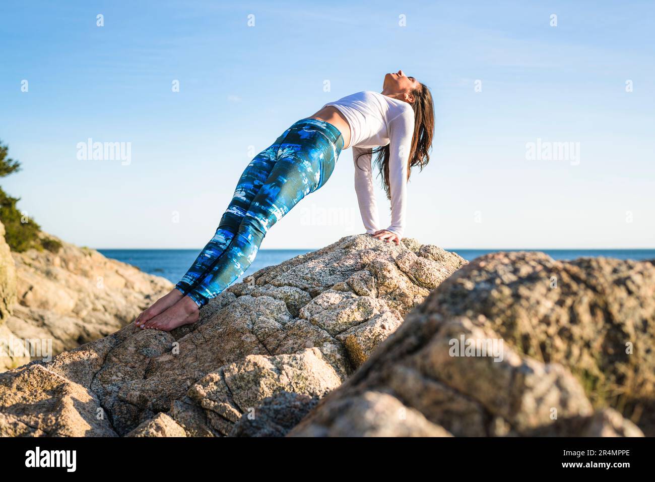 Young Woman doing Yoga on the rocks at Golden Hour Stock Photo