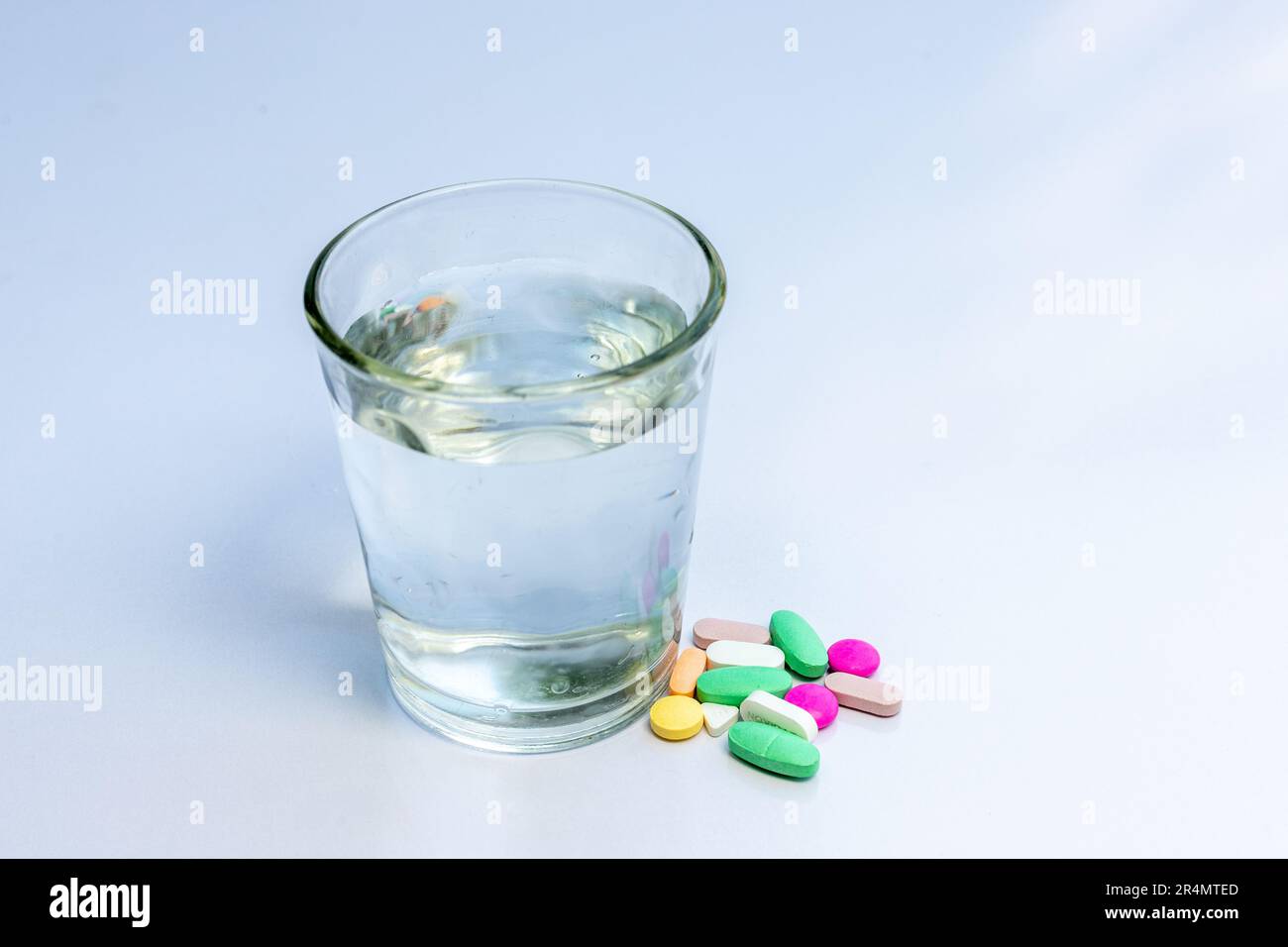 Various medical pills and tablets with a glass full of water Stock Photo