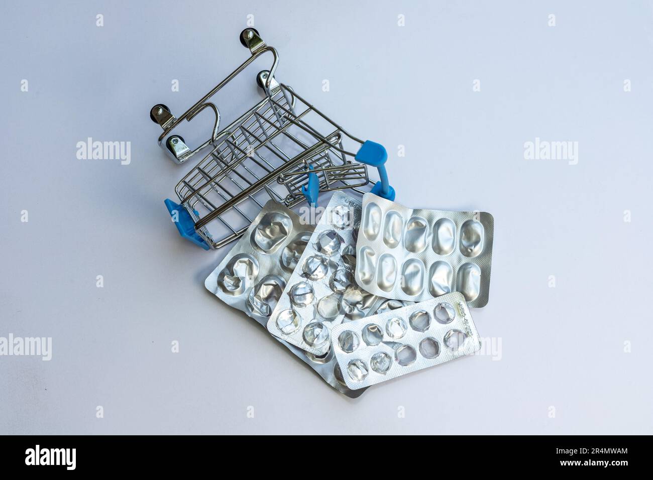 Consumed pills and tablet strips in a mini shopping trolley. Medicine consumption concept. Stock Photo