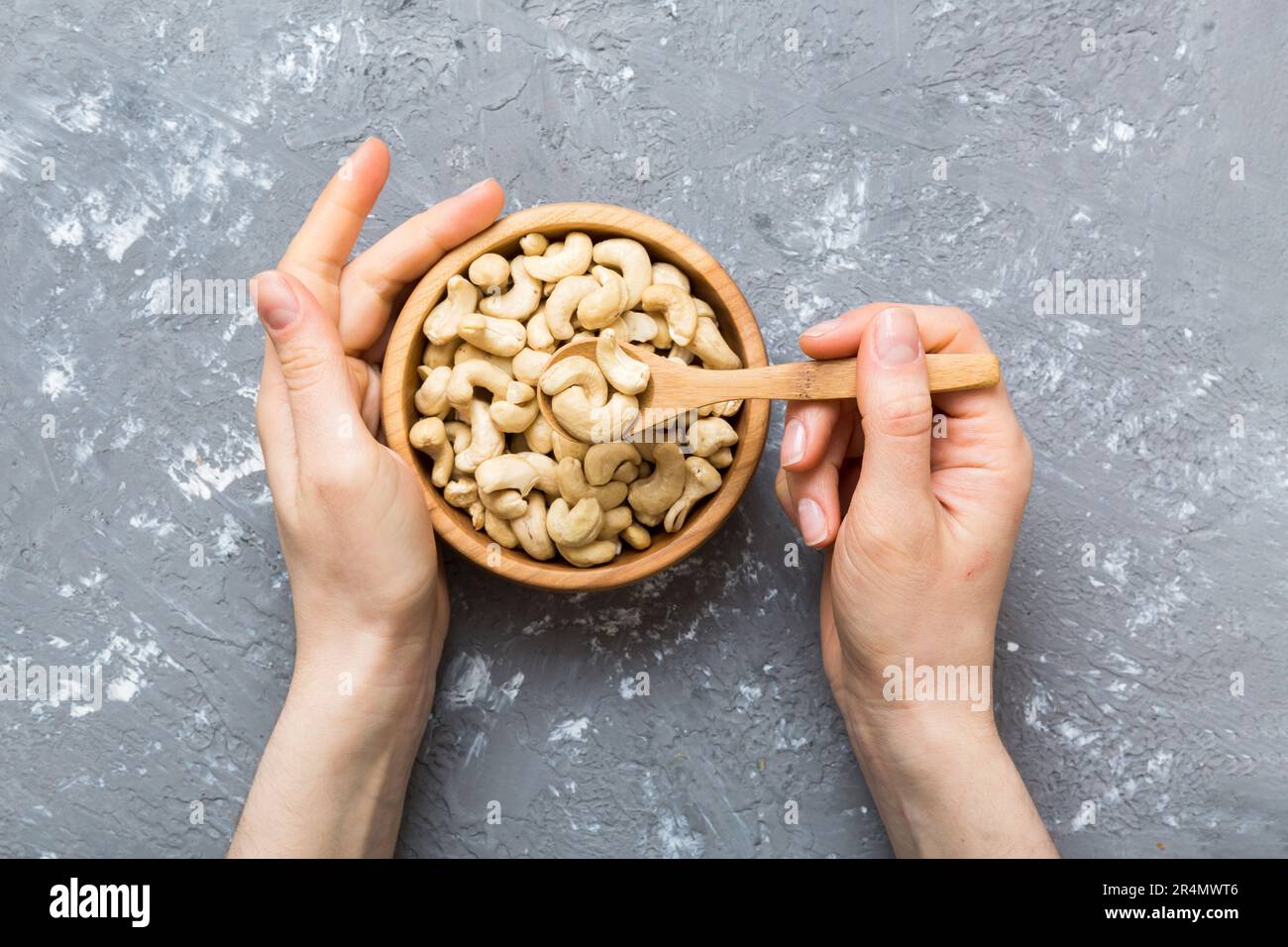 Woman hands holding a wooden bowl with cashew nuts. Healthy food and