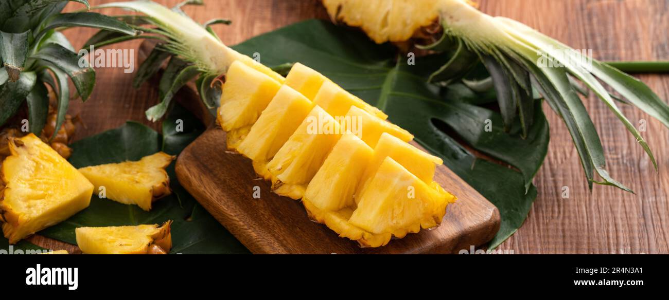 Close up of fresh cut pineapple on a tray over dark wooden table background. Stock Photo