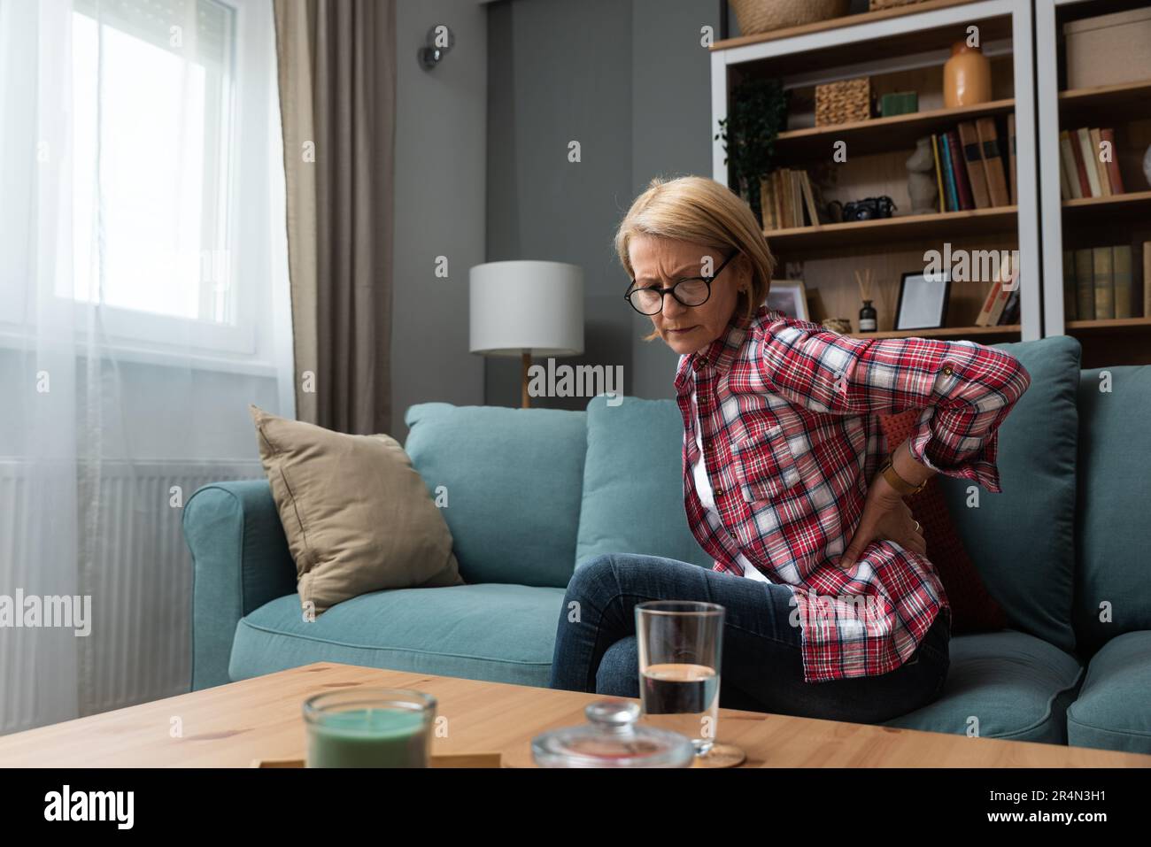 Pensive thoughtful middle aged lady looking away sit alone at home feel anxious lonely, sad depressed melancholic old mature woman suffer from sorrow Stock Photo