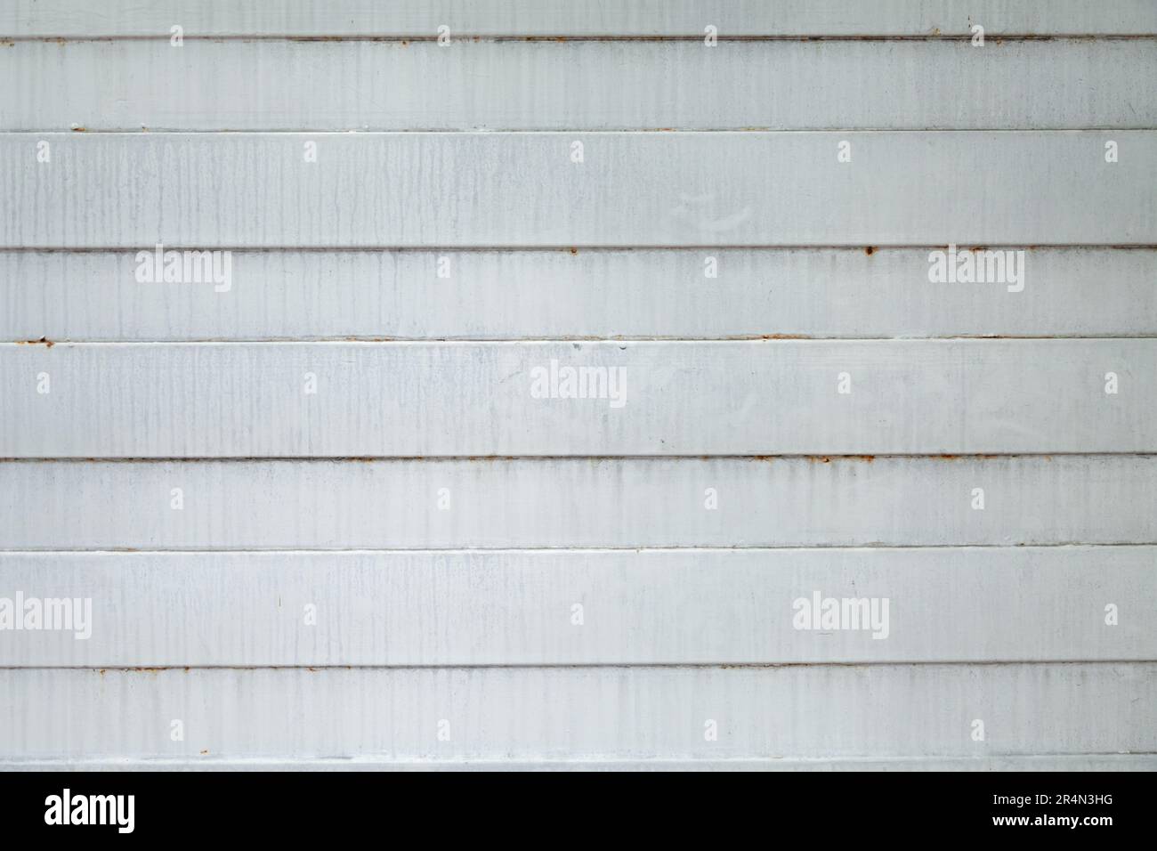 Gray painted surface of a corrugated metal gate with ridges and grooves. Old stained metallic wall with a simple geometric pattern of horizontal lines Stock Photo
