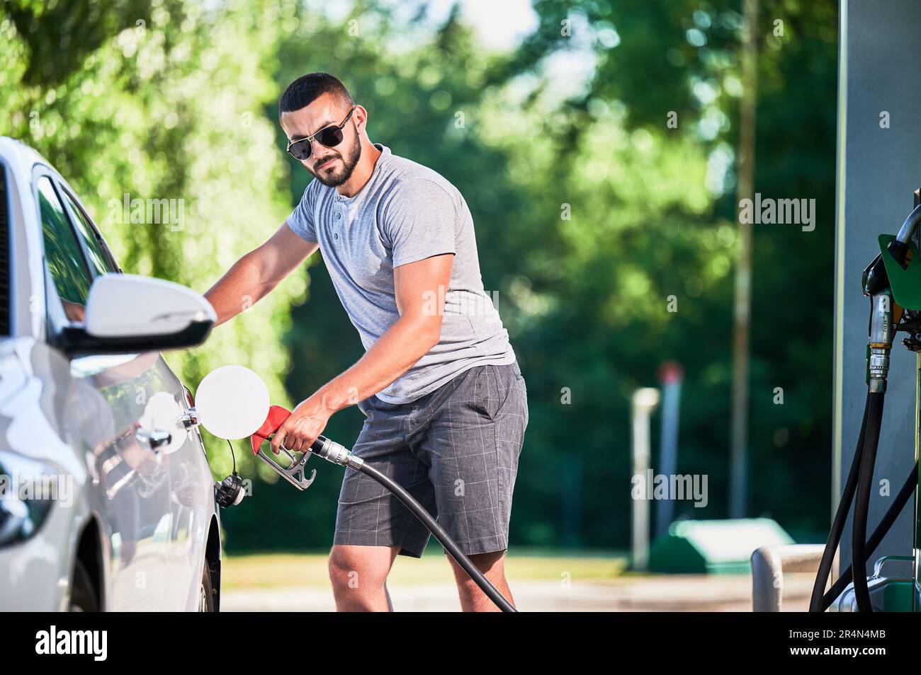 Driver with gasoline pump refilling car gas tank. Confident man