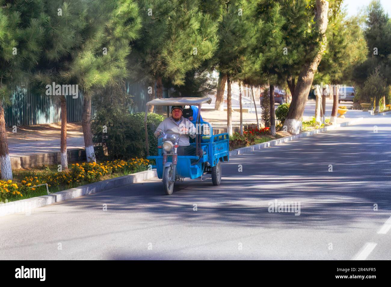 Tajikistan road. October 17, 2019: Young man ride on an old motorcycle with a back cart. Stock Photo